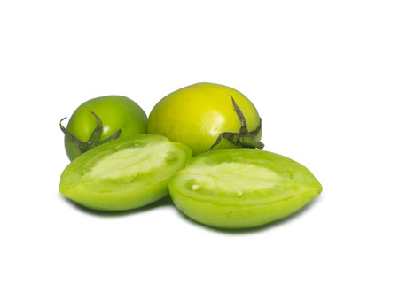 Green tomatoes on a white background. The concept of an unripe vegetable. Half cut tomato. Salting product. Health food. Place for writing text. Tomatoes lady's fingers.の写真素材