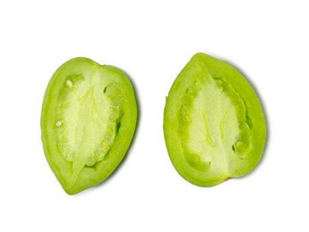 Green tomatoes on a white background. The concept of an unripe vegetable. Half cut tomato. Salting product. Health food. Place for writing text. Tomatoes lady's fingers.の写真素材