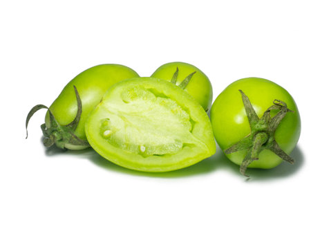 Green tomatoes on a white background. The concept of an unripe vegetable. Salt preparation. Salting product. Healthy food. Place for writing text. An unripe fruit picked from a bush. Tomatoes lady's fingers. pulpの写真素材