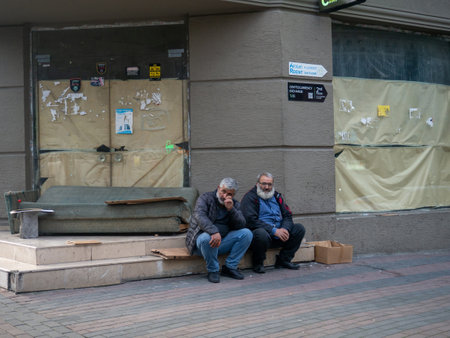 Batumi, Georgia. 21/11/2022 Two men are sitting against a wall outside. old area. Abandoned.のeditorial素材