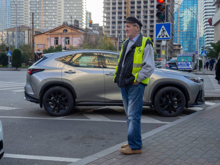 Batumi, Georgia. 11.23.2022 Old parking attendant. Man at work. street work. The roadway. looking at carsのeditorial素材