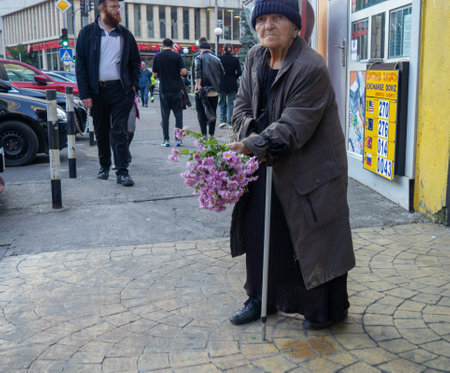 Batumi, Georgia. 11.23.2022 Street scene. A woman is selling flowers. Bouquet of flowers in hands. urban environment. Sidewalk with pedestrians. Poor manのeditorial素材
