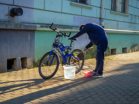 A man cleans his bike on the street. transport service. Bicycle breakdown. Repairの写真素材