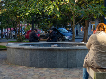 Batumi, Georgia. 23/11/2022 People sit next to on-working fountain in the park in autumn. Not a season. There is no water. Old fountain without waterのeditorial素材