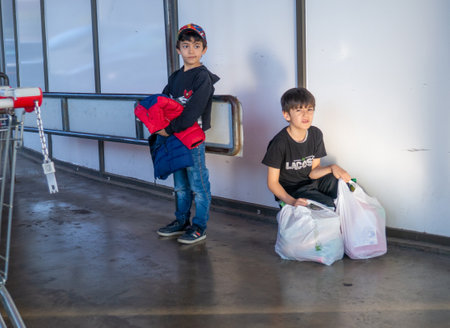 Batumi, Georgia. 23/11/2022 Boys with packages are waiting for their parents from the store. Children are resting. product packages.のeditorial素材