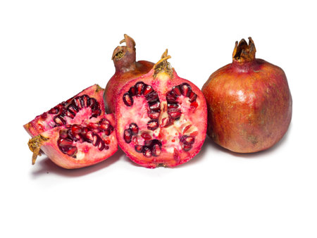 Sliced pomegranate on a white background. Juicy fruit with seeds. Pieces of red fruit. Juicy pulp. pomegranate isolate. Juice ingredient. Vegetarianismの写真素材