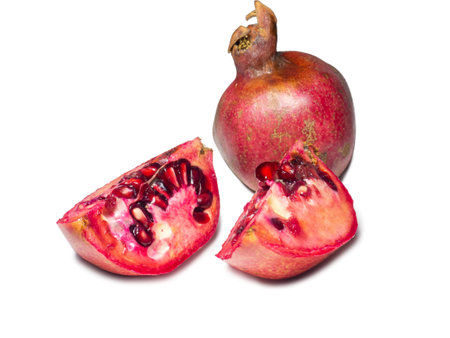 Sliced pomegranate on a white background. Juicy fruit with seeds. Pieces of red fruit. Juicy pulp. pomegranate isolate. Juice ingredient. Vegetarianismの写真素材
