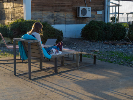 The girl is sitting on a lounger with a laptop. Resort work. Sits in social networks. internet network. The concept of working remotelyの写真素材