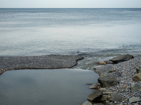 The place where a small river flows into the sea. Winter on the Black Sea. Empty coast. Beach of boulders and small pebbles. river mouthの写真素材