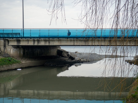A man walks along the bridge along the seashore. Walking in the resort in the winter season. The man in the hood. Coast of the Black Sea. Batumiの写真素材