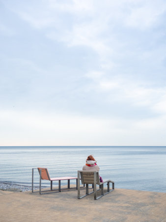 Benches for lying by the sea. Sun loungers in the park against the background of the sea. Benches in the park in the southern resort.  woman sits alone.の写真素材