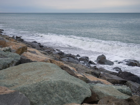 resort in winter. The rocky shore is washed by the waves in cloudy weather. Black Sea coast. The coast of Batumi. Nature in shades of grey. Grey. boring landscapeの写真素材