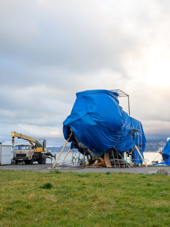 large yacht is covered with a tarpaulin. The ship is under repair. The yacht is on the shore.の写真素材