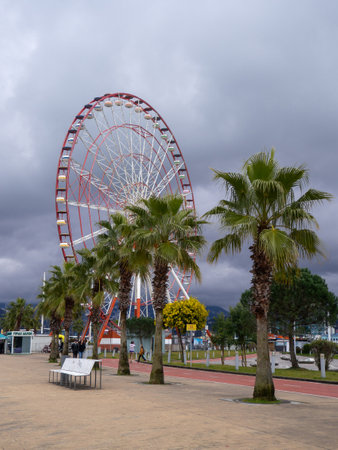 Batumi, Georgia. 02.10.2023 Ferris wheel on a cloudy day. Cloudy sky. Ferris wheel in an amusement park. Winter in the Black Sea resort. Batumi.のeditorial素材