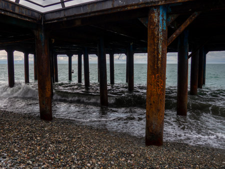 Metal pier on columns. Construction on the sea.Rusty pier. Resort place in winter on a cloudy day.の写真素材