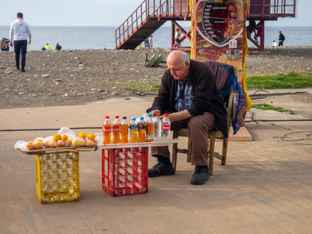 Batumi, Georgia. 03.11.2023 People in the park. Batumi boulevard. Tourist place. A man sells homemade wine and lemons. Sale on the street.のeditorial素材