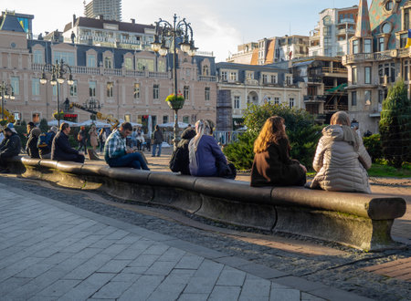 Batumi, Georgia. 12.18.2023 People are sitting on a long bench. Rest in the park. Infrastructure for recreation. Unusual benchのeditorial素材