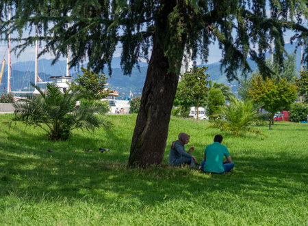 Batumi, Georgia. 07.15.2023. Rest in the park of the southern city. Picnic on the grass. Family relationships and friendship. People at the resort are resting.のeditorial素材