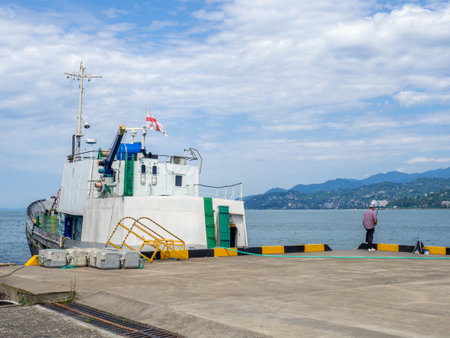 Batumi, Georgia. 07.15.2023 Fishermen are fishing with rods in the port area. People go fishing next to a moored ship. Hobbies for men. Life in a port cityのeditorial素材