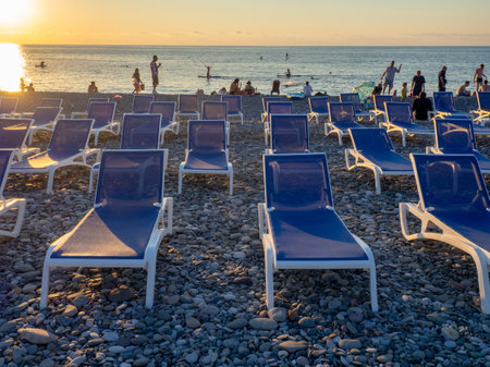 Batumi, Georgia. 07.19.2023 Beach chairs. Lots of empty sunbeds on the pebbles. The concept of commerce on the beach. Sunbed rental at the resort. At sunset. Rest of people on the sea.のeditorial素材