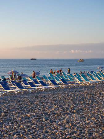 Batumi, Georgia. 07.19.2023 Beach chairs. Lots of empty sunbeds on the pebbles. The concept of commerce on the beach. Sunbed rental at the resort. At sunset. Rest of people on the sea.のeditorial素材