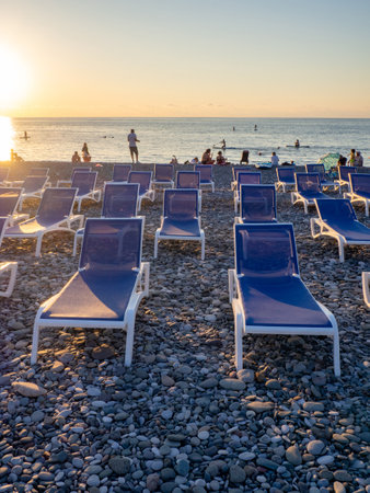 Batumi, Georgia. 07.19.2023 Beach chairs. Lots of empty sunbeds on the pebbles. The concept of commerce on the beach. Sunbed rental at the resort. At sunset. Rest of people on the sea.のeditorial素材