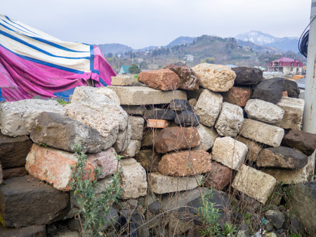 A pile of various stones stacked on top of each other. Masonry. Wall of stones. Village. fragile buildingの写真素材
