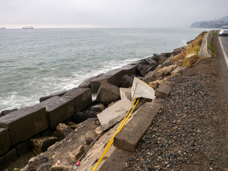 Dangerous place. Collapsed road barrier on a mountainside. Old blocks of fortifications of the coast. Concrete structures on the shore. Protection against storms, waves and avalanches. wave movementの写真素材