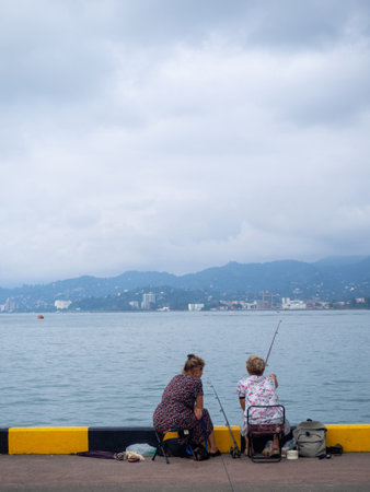 Fishing women. Fishermen near the ships. People at the pier. Favorite hobby. in port. family food. people with fishing rodsの写真素材