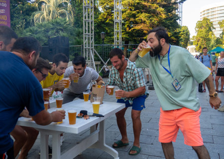 Batumi, Georgia. 08.19.2023  Beer Festival. Men drink beer. Who will drink faster. Festival competition.   People relax and drink. Holiday soft drink. Holiday on the street.のeditorial素材