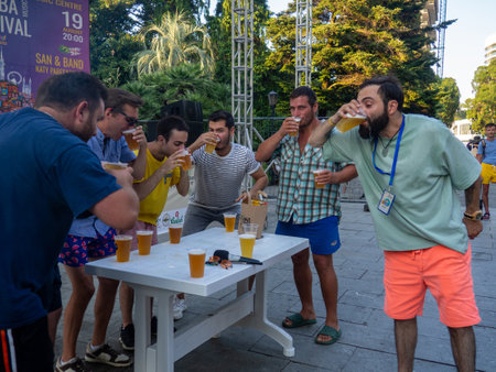 Batumi, Georgia. 08.19.2023  Beer Festival. Men drink beer. Who will drink faster. Festival competition.   People relax and drink. Holiday soft drink. Holiday on the street.のeditorial素材