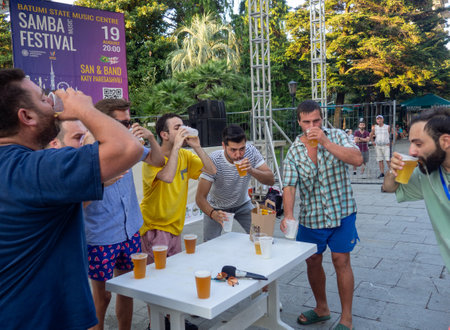 Batumi, Georgia. 08.19.2023  Beer Festival. Men drink beer. Who will drink faster. Festival competition.   People relax and drink. Holiday soft drink. Holiday on the street.のeditorial素材