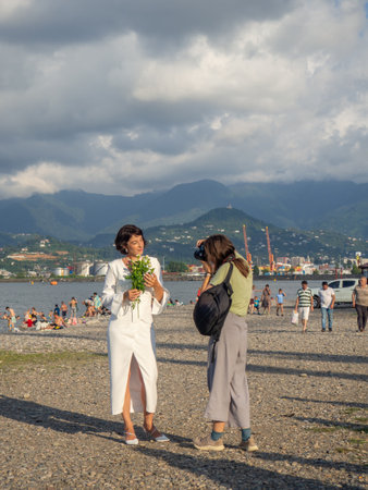 Batumi, Georgia. 08.24.2023 Photographer at work. The girl takes a picture of the girl. Photo session at the resort. Working with the cameraのeditorial素材