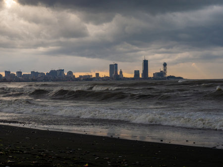 center of Batumi against the backdrop of big waves. The city against the backdrop of the rough sea. Houses in the distance. Big waves on the sea. After the storm. Bad weather. Danger. Element on the Black Sea. Architecture of Batumiの写真素材