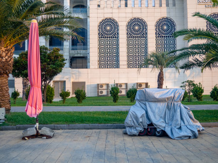 Vehicles at the resort are covered with tarps. Bicycles and scooters at the resort. The concept of the end of the holiday season. Rain protection. Business of entertainment on vacationの写真素材