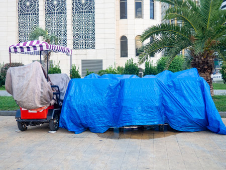 Vehicles at the resort are covered with tarps. Bicycles and scooters at the resort. The concept of the end of the holiday season. Rain protection. Business of entertainment on vacationの写真素材