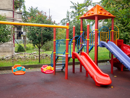 Plastic playground. Safe game for children. City infrastructure. Swings and slides made of plastic. Entertainment. Playground in the yard. Spiral slideの写真素材