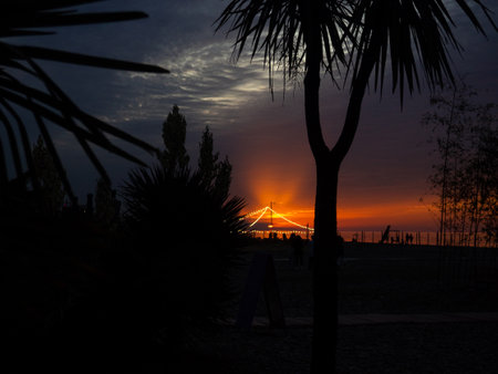 Bright sunset against the backdrop of a restaurant on the seashore. Restaurant lights. Sunset at the resort. Quiet evening lights.の写真素材