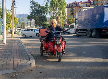 Batumi, Georgia. 04/11/2023 tricycle electric motorcycle. A man is driving through the city. Local resident in Georgia on the road. Kral bossのeditorial素材