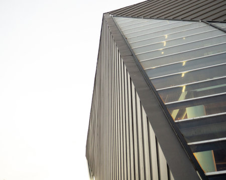 Modern geometric architecture from a special angle. Part of a modern gloomy building. Gray building and gray sky.の写真素材