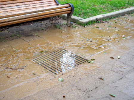 A storm drain filled with water in a park. Clogged storm drain. Infrastructure not working. Utility accident. After the rainの写真素材