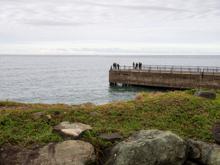 People on an empty pier in cloudy weather. Marina on the Black Sea in winter. Turkish provincial resort.の写真素材