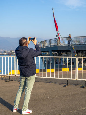 Batumi , Georgia. 03.05.2024  A warship is moored at the port. Patrol ship. Resort place.  A tourist takes photographs of military personnel on his phone.のeditorial素材