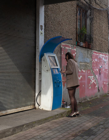 Batumi, Georgia. 03.18.2024 Beautiful girl at an ATM in the slums. Security concept. Receiving the...
