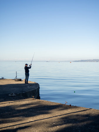 Batumi, Georgia. 02.31.2024 Fisherman with a fishing rod on the pier. Fishing. Hobbies for men. Entrance day. Fisherman silhouetteのeditorial素材