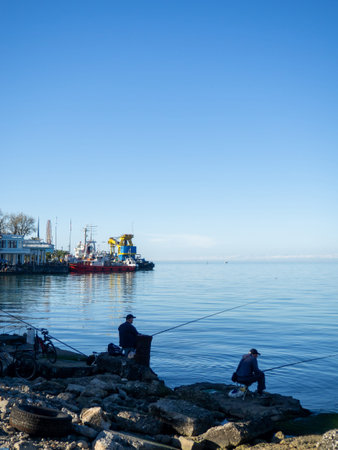 Fishermen with fishing rods on the pier. Fishing. Hobbies for men. Entrance day. Fishermen...