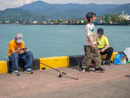 Batumi, Georgia. 10/05/2024 Fishermen in the port on the pier. Adults and children fish. Hobby. Weekend activity with familyのeditorial素材