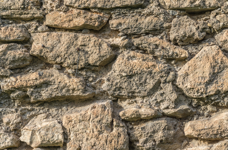 Old wall of large irregular pieces of stone ruins brown backgroundの写真素材