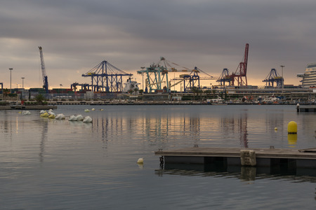 Cargo cranes working at the port, behind the sunlight between the cloudsの写真素材