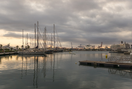 Sailboats and a a cruise ship moored in the harbor, sunrise sunlight shines through the clouds at background port panoramic viewsの写真素材